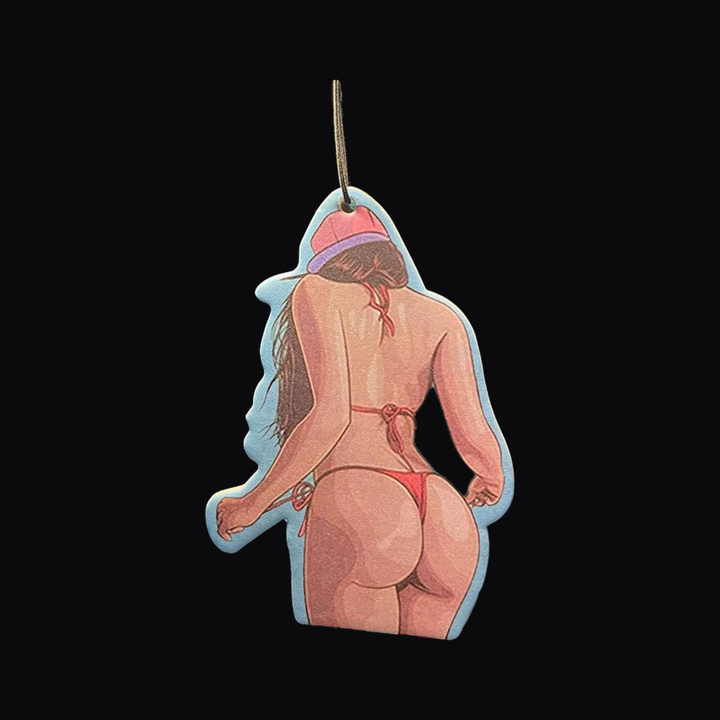 Cartoon pin up air freshener hanging from a rear view mirror at night